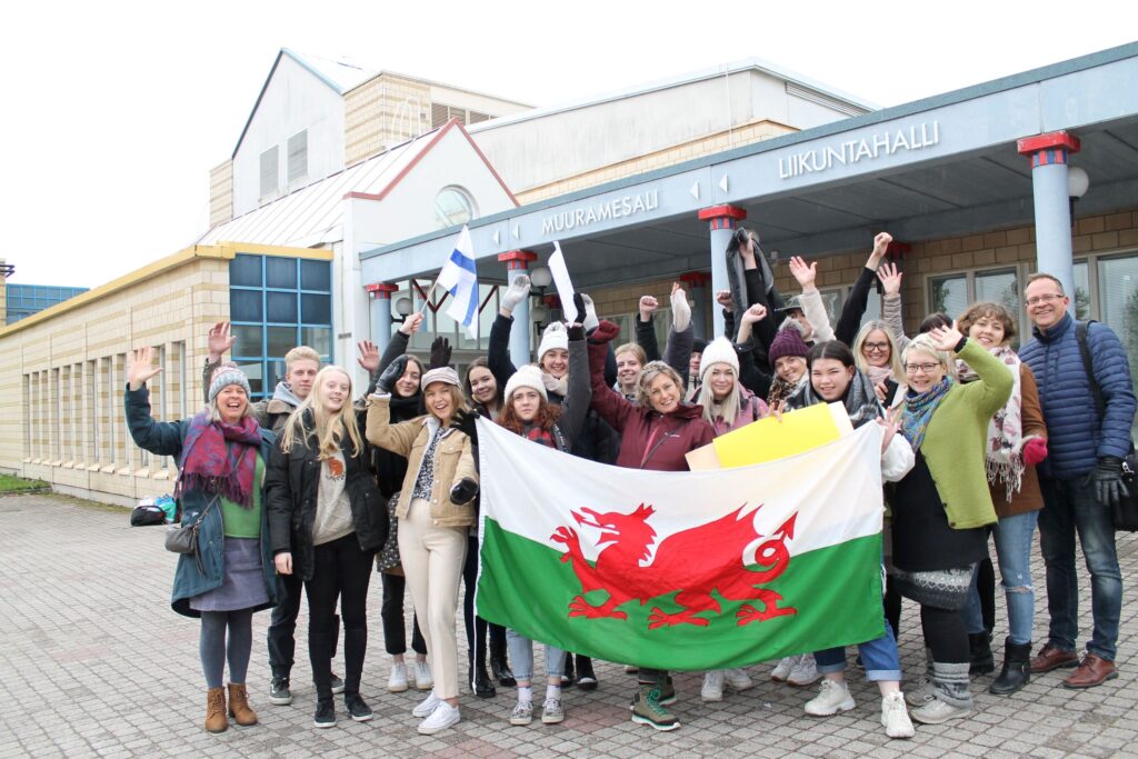 Ihmisiä Muuramesalin edustalla heiluttamassa Walesin lippua. Rewi visions -hankkeessa. 
