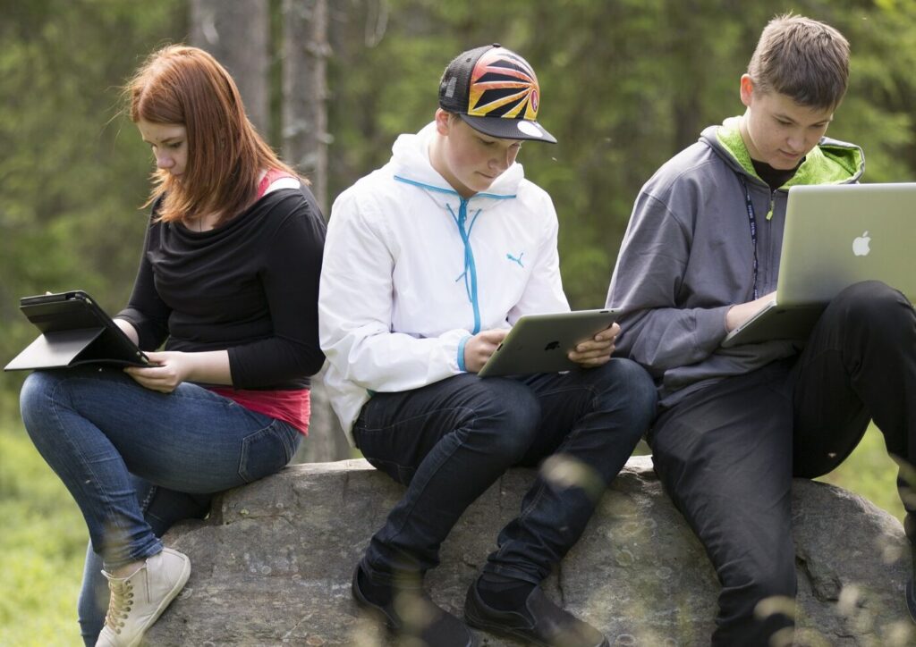 nuoret tietokoneilla metsässä