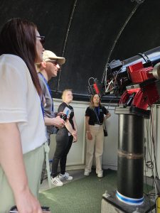 Neljä ihmistä tutkimassa observatorion kaukoputkea.