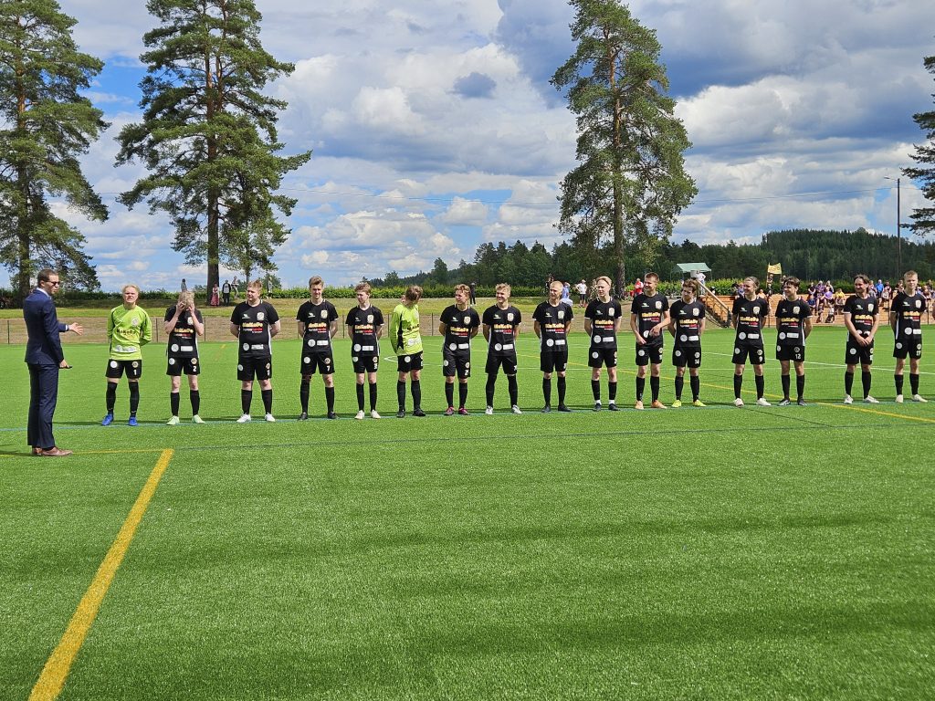 Jalkapallojoukkue HaKoPo seisoo rivissä jalkapallokentällä ennen pelin alkua.