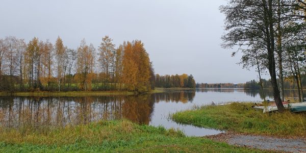 Järvi, joka kapenee salmeksi kuvan vasemmassa reunassa. Vastarannalla lehtipuita ruskassa, osasta jo pudonnut lehdet. Oikeassa reunassa on muutama soutuvene rannalla.