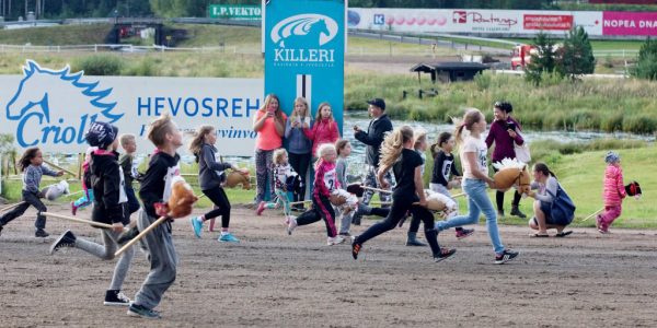 Lapset juoksevat keppihevoskisoissa.